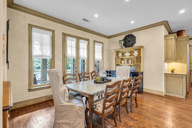 dining room with french doors, crown molding, and hardwood / wood-style flooring