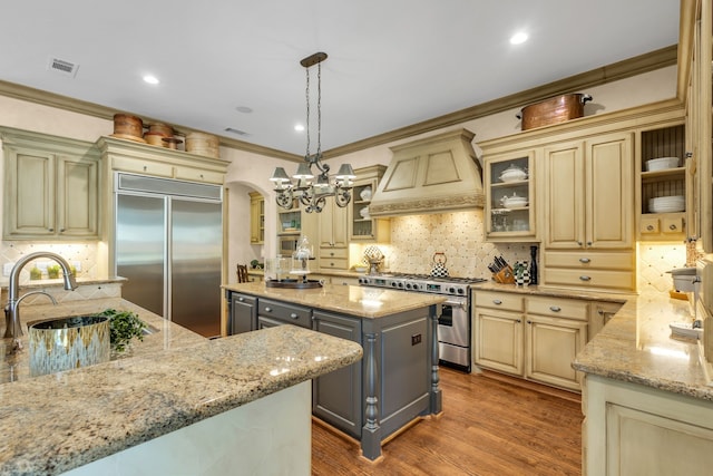 kitchen featuring light stone counters, pendant lighting, gray cabinetry, a kitchen island, and high quality appliances