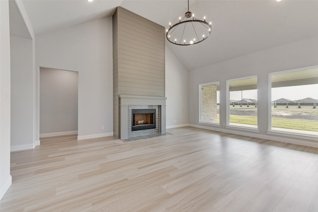 unfurnished living room with high vaulted ceiling, a notable chandelier, and light hardwood / wood-style flooring