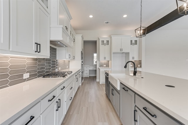 kitchen featuring decorative light fixtures, sink, stainless steel appliances, and white cabinets