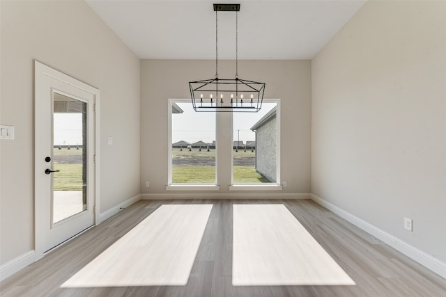 unfurnished dining area with a notable chandelier and light wood-type flooring