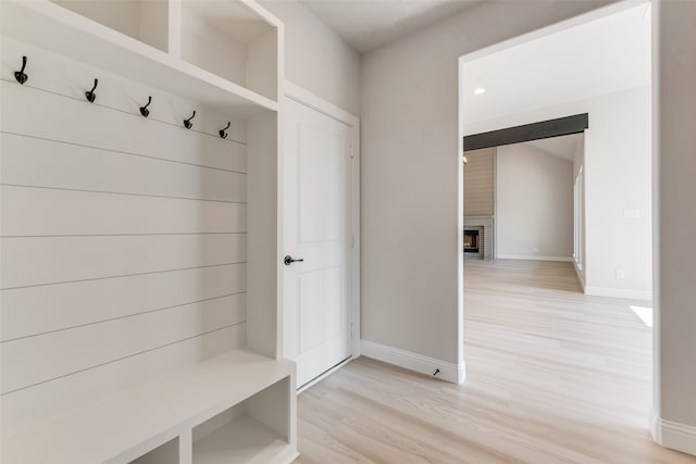 mudroom with a fireplace and light hardwood / wood-style floors