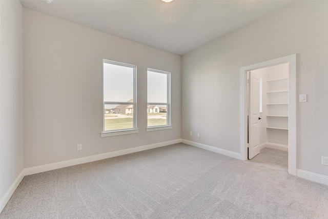 unfurnished bedroom featuring light carpet, a walk in closet, and a closet