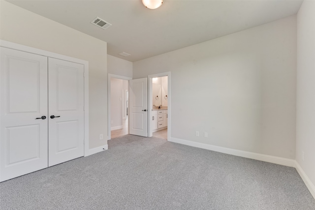 unfurnished bedroom featuring light colored carpet, a closet, and connected bathroom