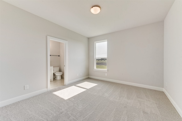 unfurnished bedroom featuring light colored carpet and ensuite bath