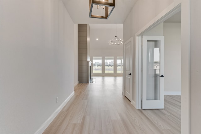 corridor featuring a notable chandelier and light hardwood / wood-style flooring