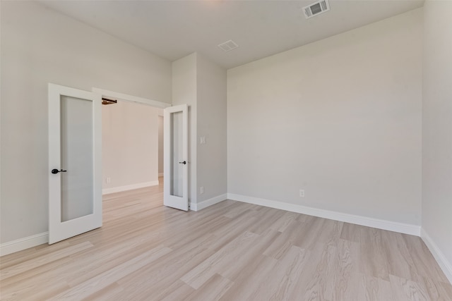 unfurnished room featuring french doors and light hardwood / wood-style flooring