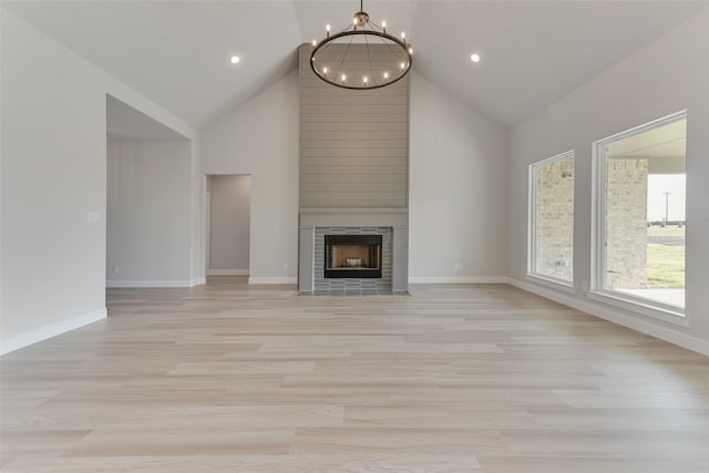 unfurnished living room featuring light wood-type flooring, a fireplace, and high vaulted ceiling