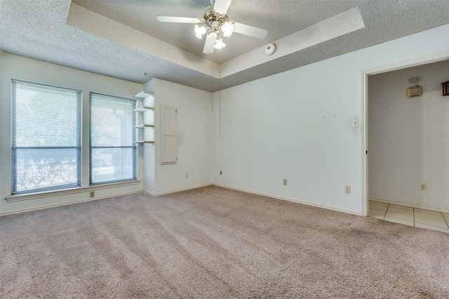 carpeted spare room with a tray ceiling, ceiling fan, and a textured ceiling