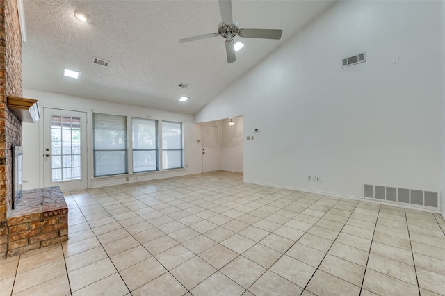 unfurnished room with ceiling fan, light tile patterned flooring, a textured ceiling, high vaulted ceiling, and a fireplace