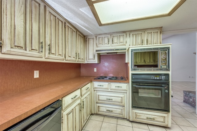 kitchen featuring a textured ceiling, black appliances, cream cabinets, and light tile patterned floors