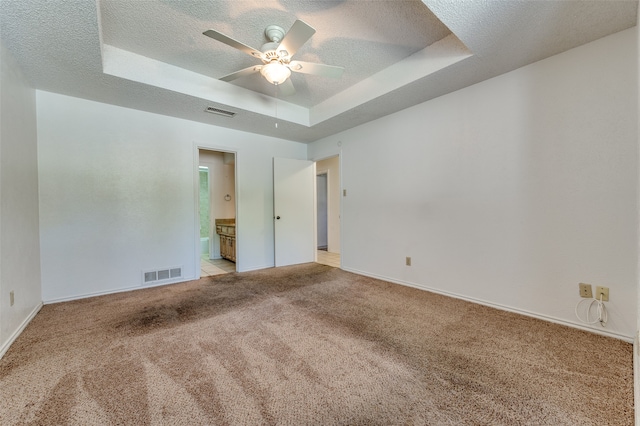 carpeted spare room with a textured ceiling, a raised ceiling, and ceiling fan