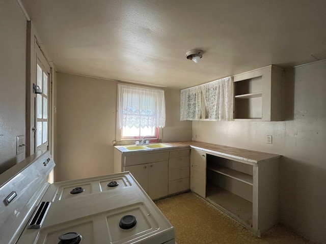 kitchen with white cabinets, white range, and sink