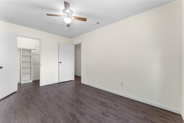 unfurnished bedroom featuring dark wood-type flooring, ceiling fan, a spacious closet, and a closet