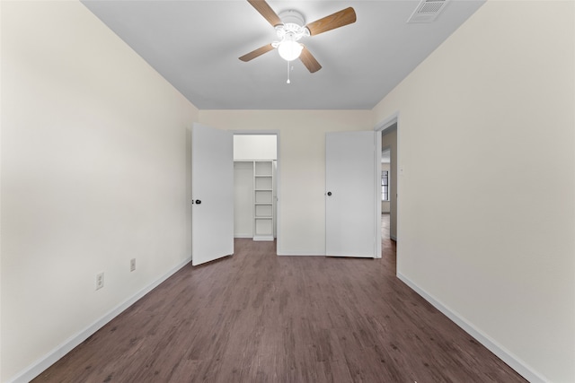 unfurnished bedroom with hardwood / wood-style flooring, a walk in closet, a closet, and ceiling fan