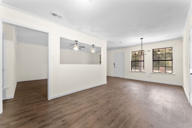 spare room featuring dark wood-type flooring, ornamental molding, and ceiling fan with notable chandelier