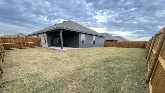 rear view of house featuring a lawn and a patio