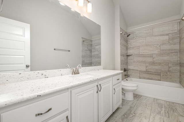 full bathroom with vaulted ceiling, vanity, tiled shower / bath, and toilet