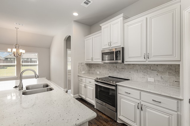 kitchen featuring appliances with stainless steel finishes, white cabinetry, light stone counters, lofted ceiling, and sink