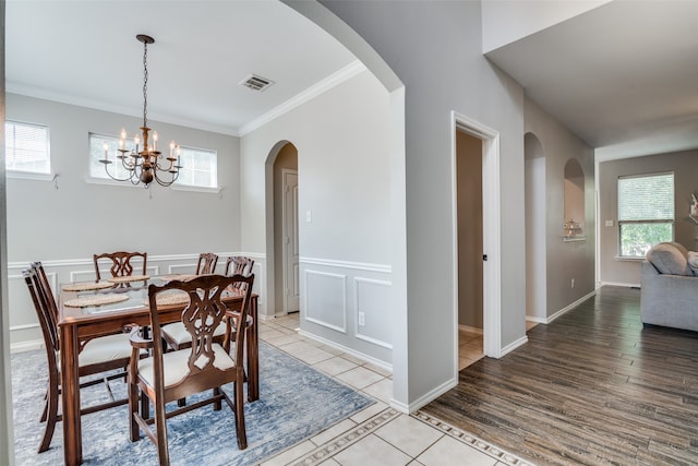 dining space with a healthy amount of sunlight, crown molding, an inviting chandelier, and light hardwood / wood-style flooring