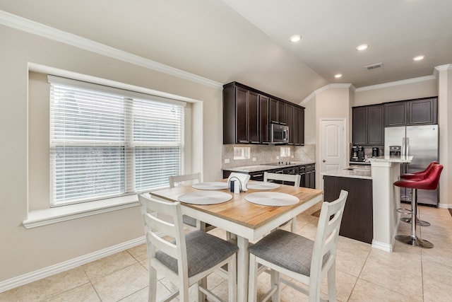 tiled dining area featuring ornamental molding and lofted ceiling