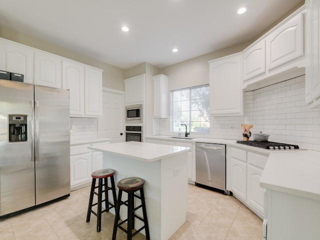 kitchen featuring a center island, sink, white cabinets, a kitchen breakfast bar, and appliances with stainless steel finishes