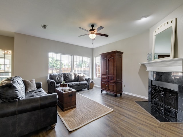 living room with ceiling fan, a fireplace, plenty of natural light, and dark wood-type flooring