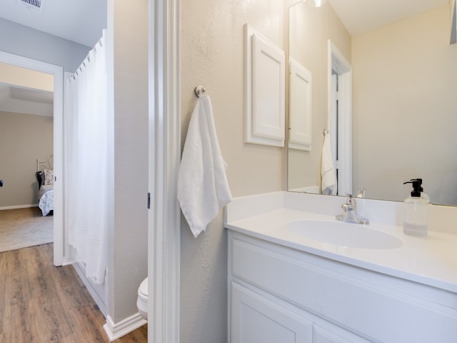 bathroom with hardwood / wood-style floors, vanity, and toilet