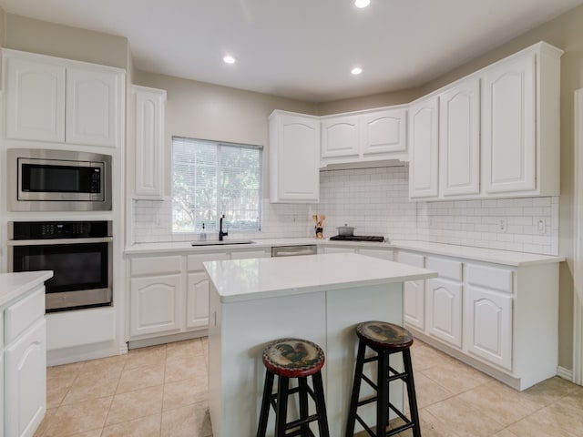 kitchen featuring appliances with stainless steel finishes, a kitchen island, sink, and white cabinets