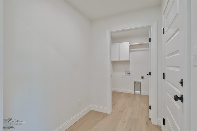 laundry area featuring washer hookup, light wood-type flooring, and cabinets