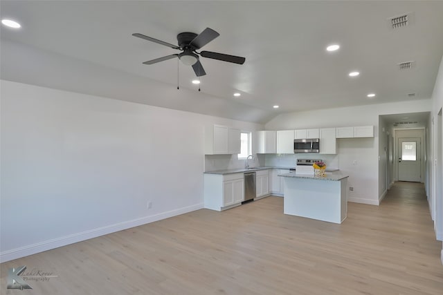 kitchen with white cabinets, a kitchen island, light stone countertops, light hardwood / wood-style floors, and stainless steel appliances