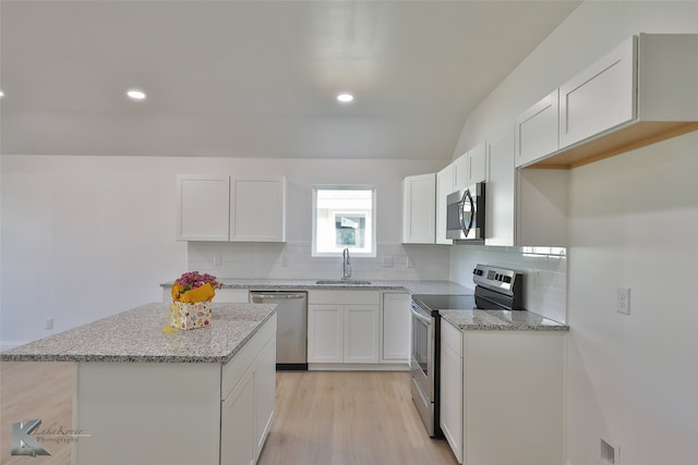 kitchen featuring appliances with stainless steel finishes, sink, a kitchen island, white cabinetry, and light hardwood / wood-style floors