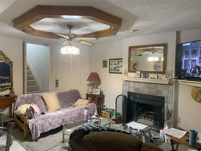 living room featuring a fireplace, a textured ceiling, stairs, and ceiling fan