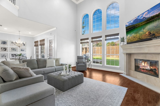 living room with ornamental molding, a chandelier, a fireplace, and dark hardwood / wood-style flooring