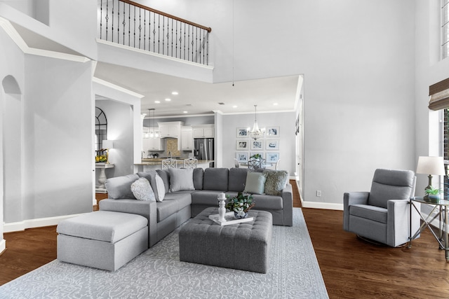 living room featuring an inviting chandelier, dark hardwood / wood-style floors, crown molding, and a high ceiling