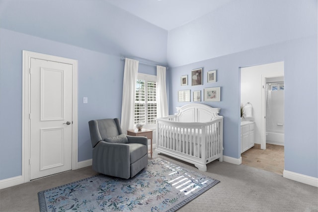 bedroom featuring ensuite bath, a crib, and light colored carpet