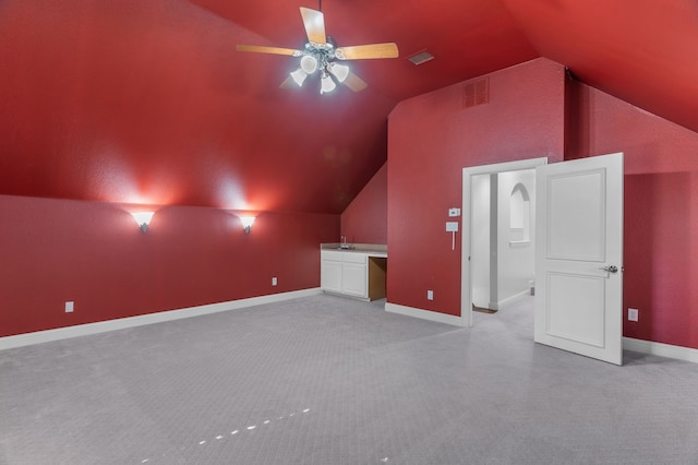 bonus room featuring lofted ceiling, built in desk, light carpet, and ceiling fan