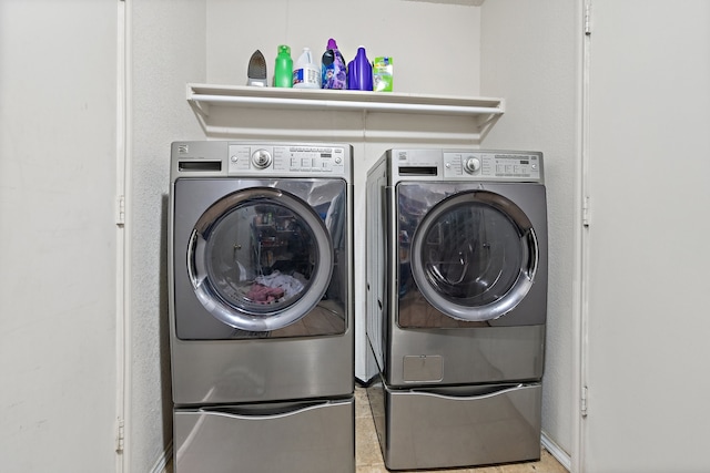 clothes washing area featuring light tile patterned floors and washing machine and dryer