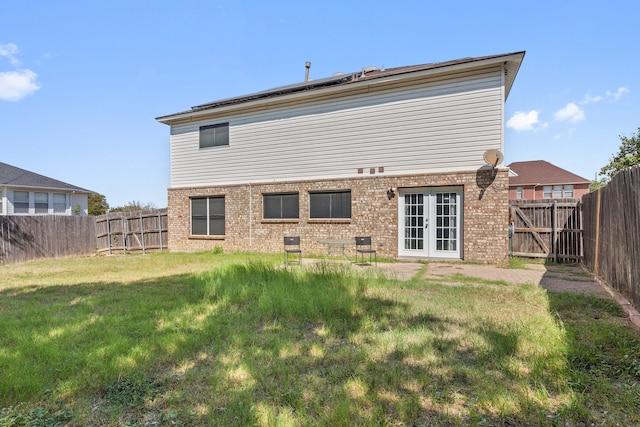 back of property with a lawn and french doors