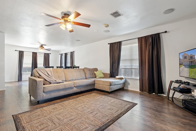 living room featuring ceiling fan, a textured ceiling, and dark wood-type flooring