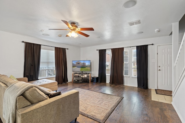 living room featuring ceiling fan, a textured ceiling, and dark hardwood / wood-style flooring