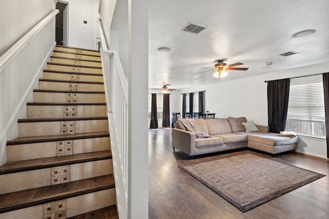 living room with a textured ceiling, wood-type flooring, and ceiling fan