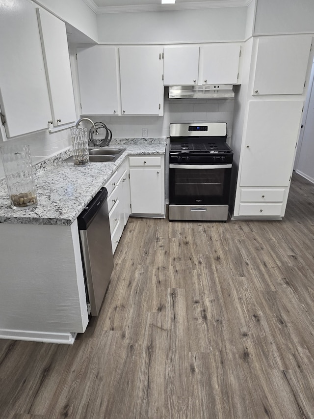 kitchen featuring appliances with stainless steel finishes, white cabinets, light stone countertops, hardwood / wood-style floors, and sink