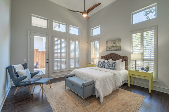 bedroom featuring a towering ceiling, dark hardwood / wood-style floors, access to exterior, and ceiling fan