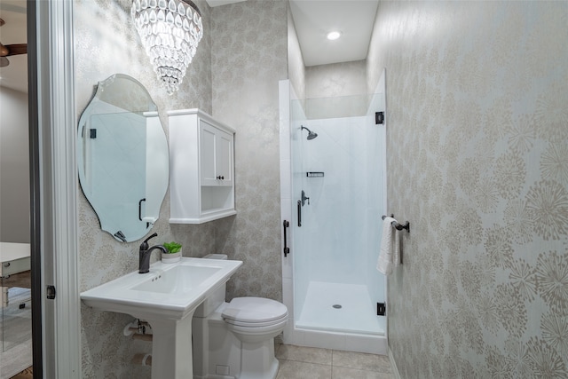 bathroom with an inviting chandelier, toilet, tile patterned flooring, and a tile shower