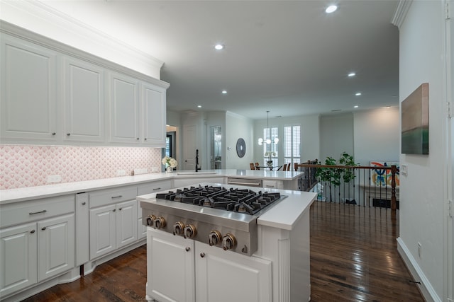 kitchen featuring white cabinets, sink, kitchen peninsula, stainless steel gas cooktop, and dark hardwood / wood-style flooring