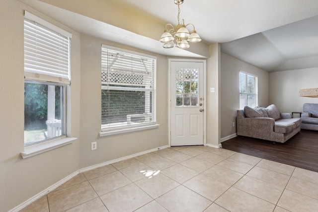 entryway with a notable chandelier, light hardwood / wood-style flooring, and vaulted ceiling