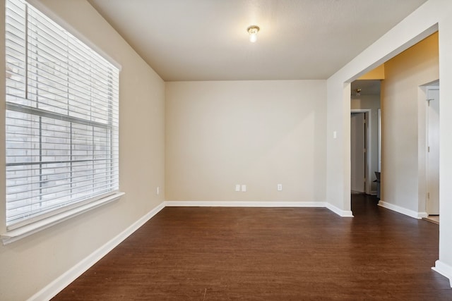 unfurnished room featuring plenty of natural light and dark hardwood / wood-style flooring