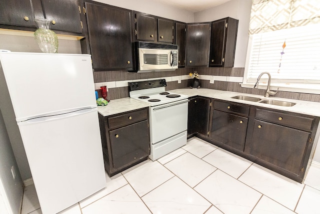 kitchen featuring white appliances, backsplash, dark brown cabinetry, and sink