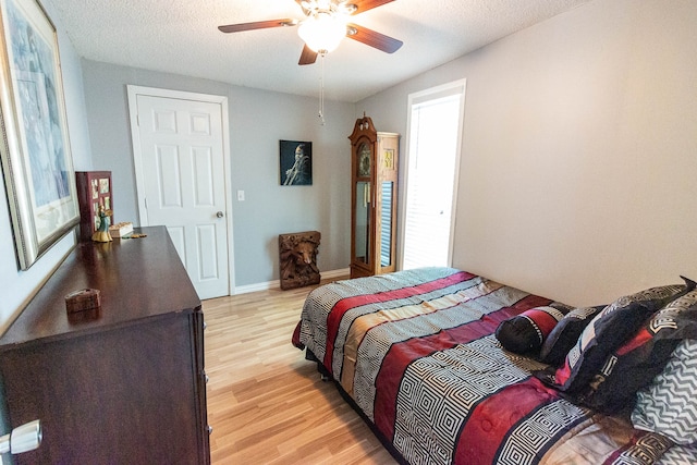 bedroom with a textured ceiling, light wood-type flooring, and ceiling fan